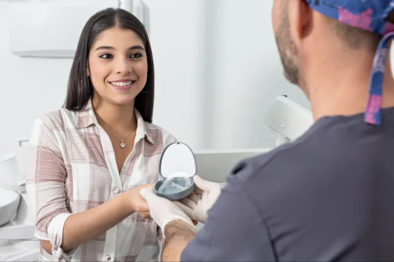 Orthodontist handing a patient their clear aligners after getting fitted.