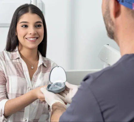 Orthodontist handing a patient their clear aligners after getting fitted.