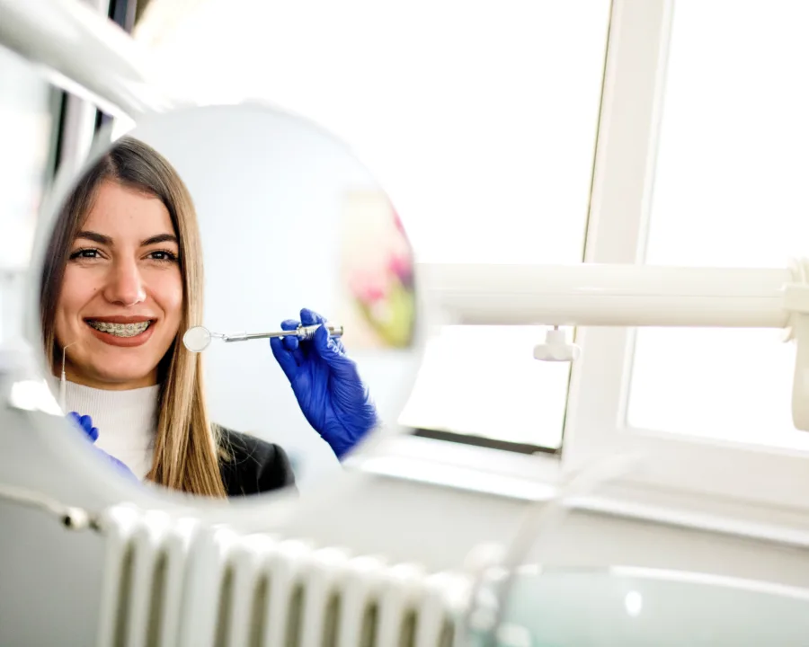 Patient looking in a mirror smiling with braces.