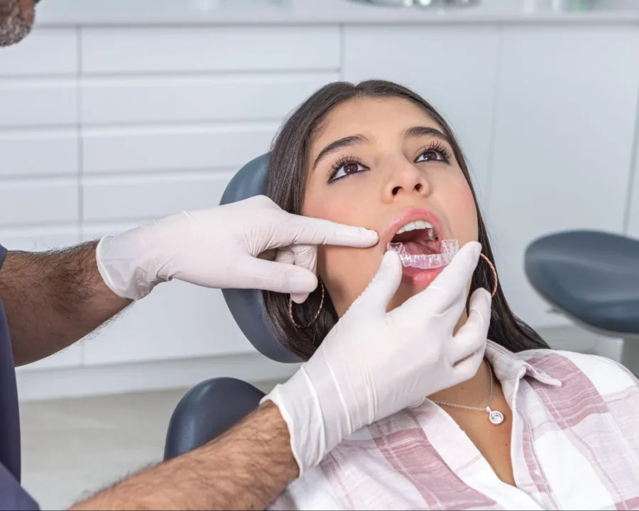 Orthodontist placing a patients clear aligners in their mouth.