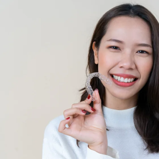 Woman smiling holding clear aligners